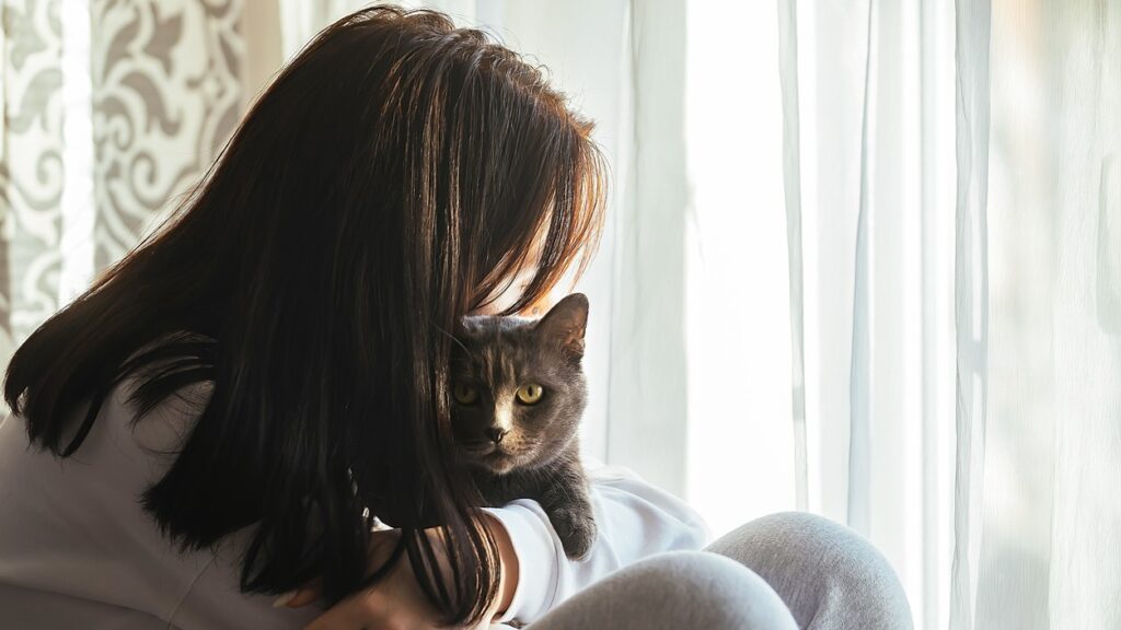 This image shows a young woman cuddling a cat - grounding techniques for feeling safe